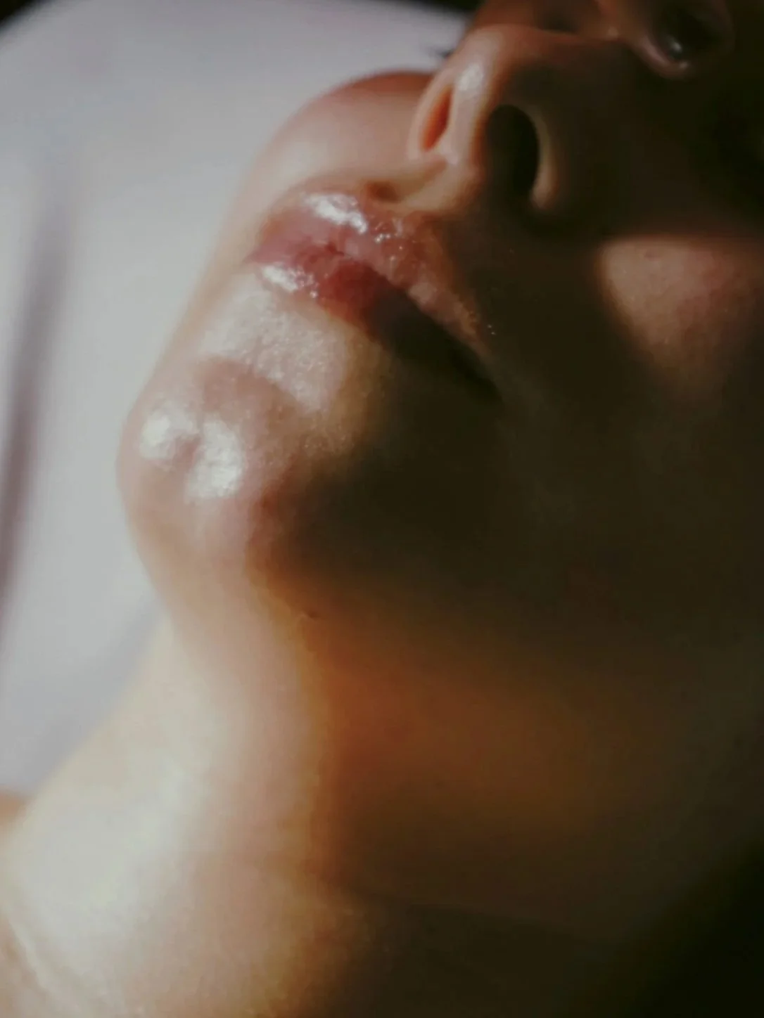 Close-up of a person's face, showing their nose, lips, and part of the eye, with wet skin and lips.