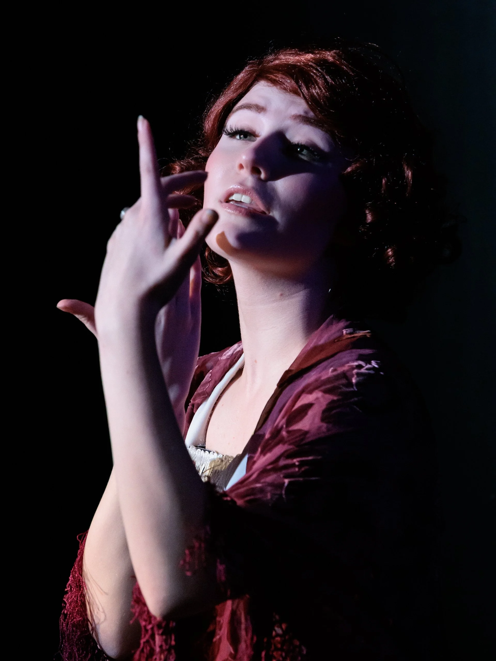Addison Skyler as Janet Van De Graaff in Drowsy Chaperone musical. A woman with short, curly red hair poses against a dark background.