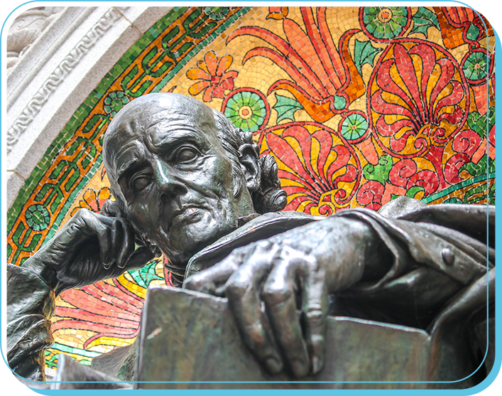 Close-up of a bronze statue of a man with a contemplative expression, resting his chin on his hand, in front of a colorful mosaic background.