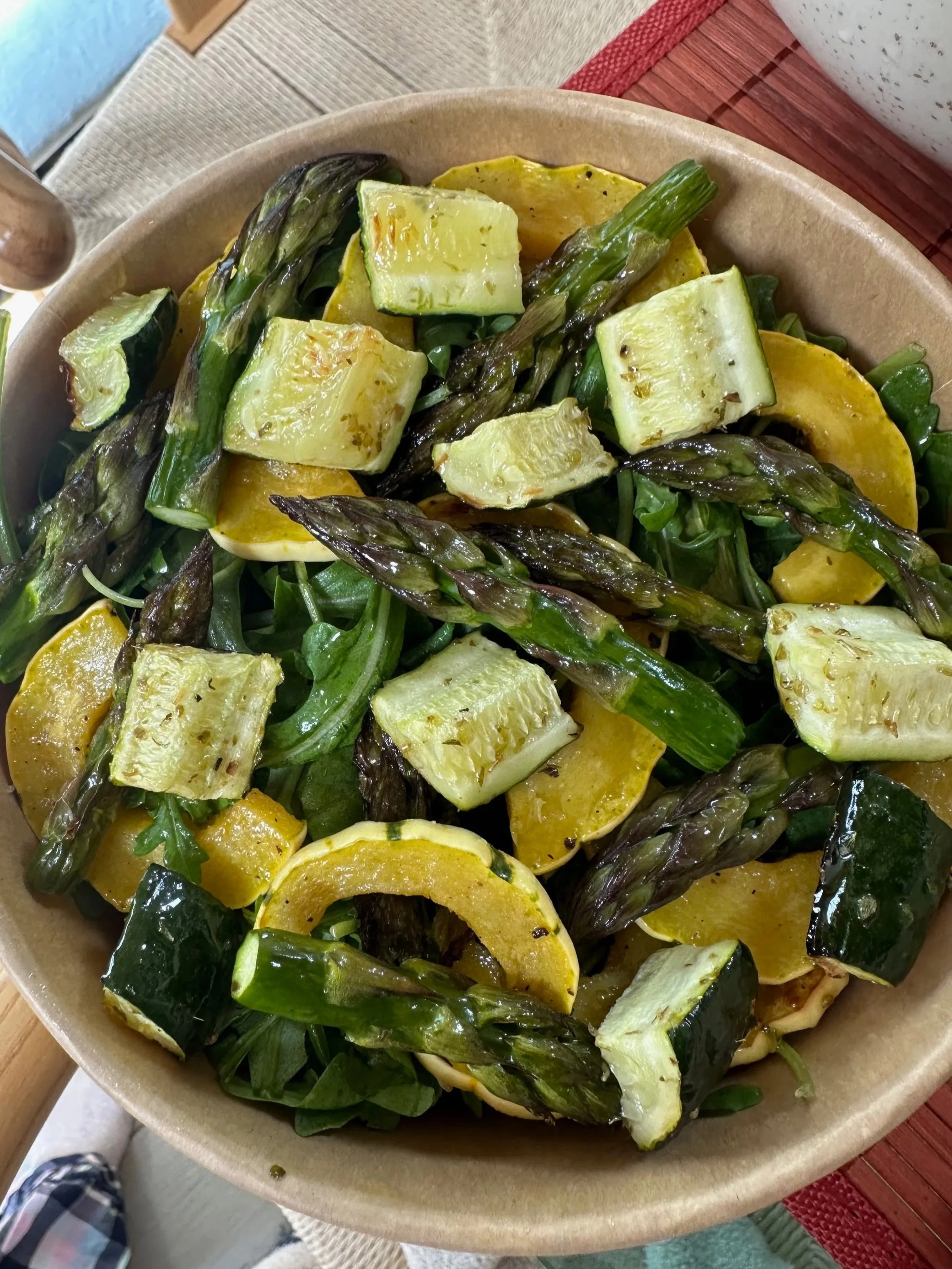 A bowl of grilled vegetables including zucchini, yellow squash, and asparagus.