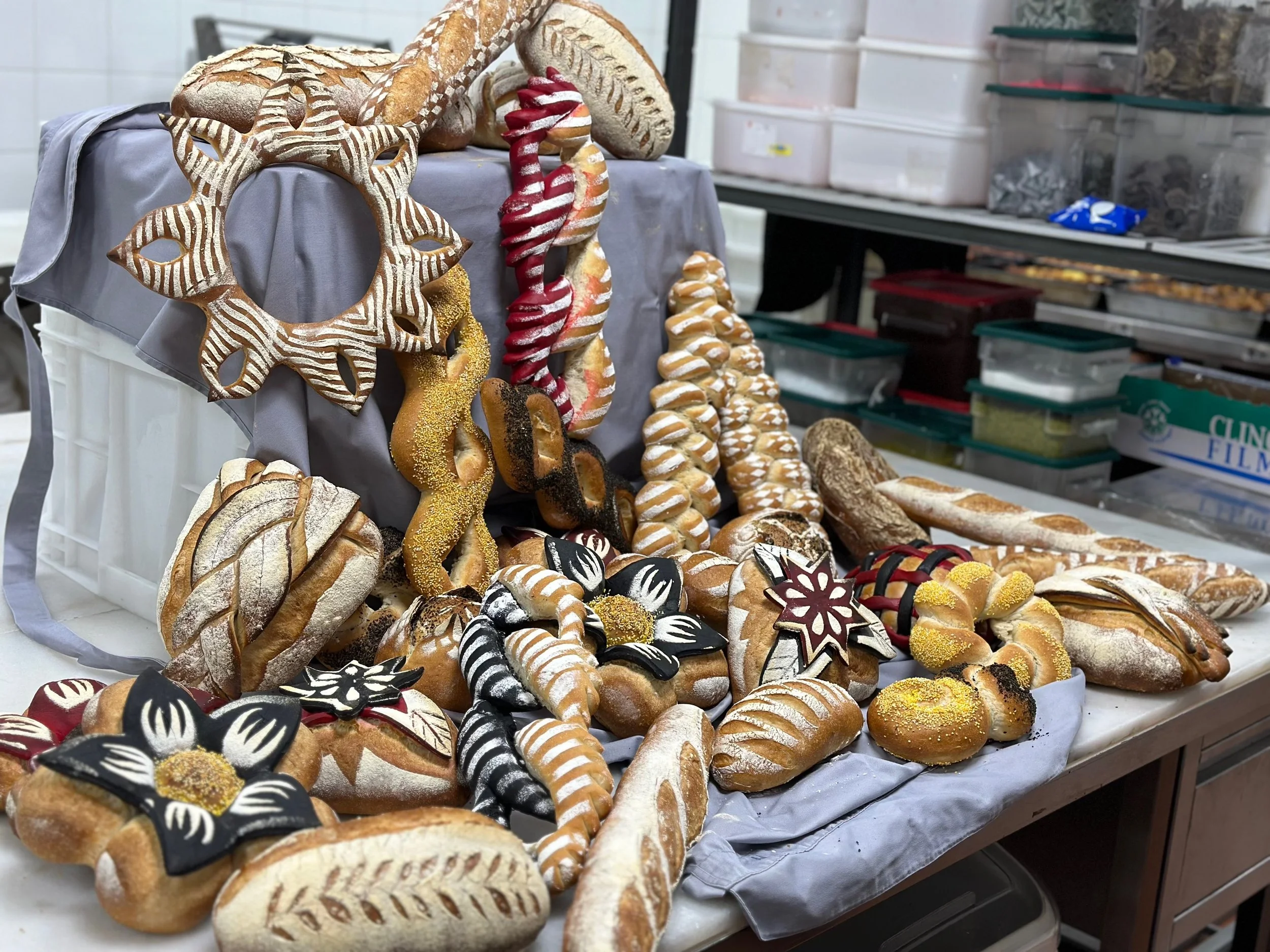 Assorted decorated bread and cookies on a table with display containers in the background.