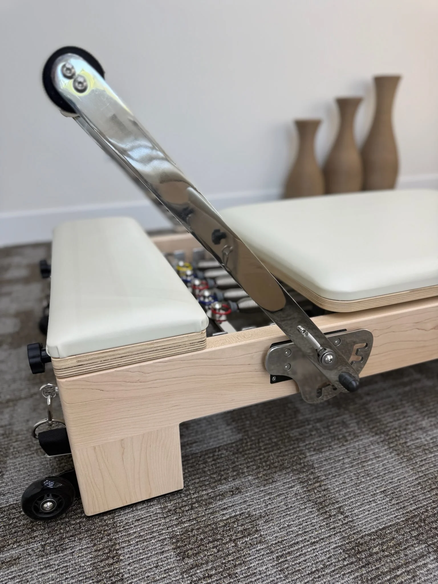 A foosball table with a wooden frame, white foam paddings, and black wheels, with a metal lever attached to the side.