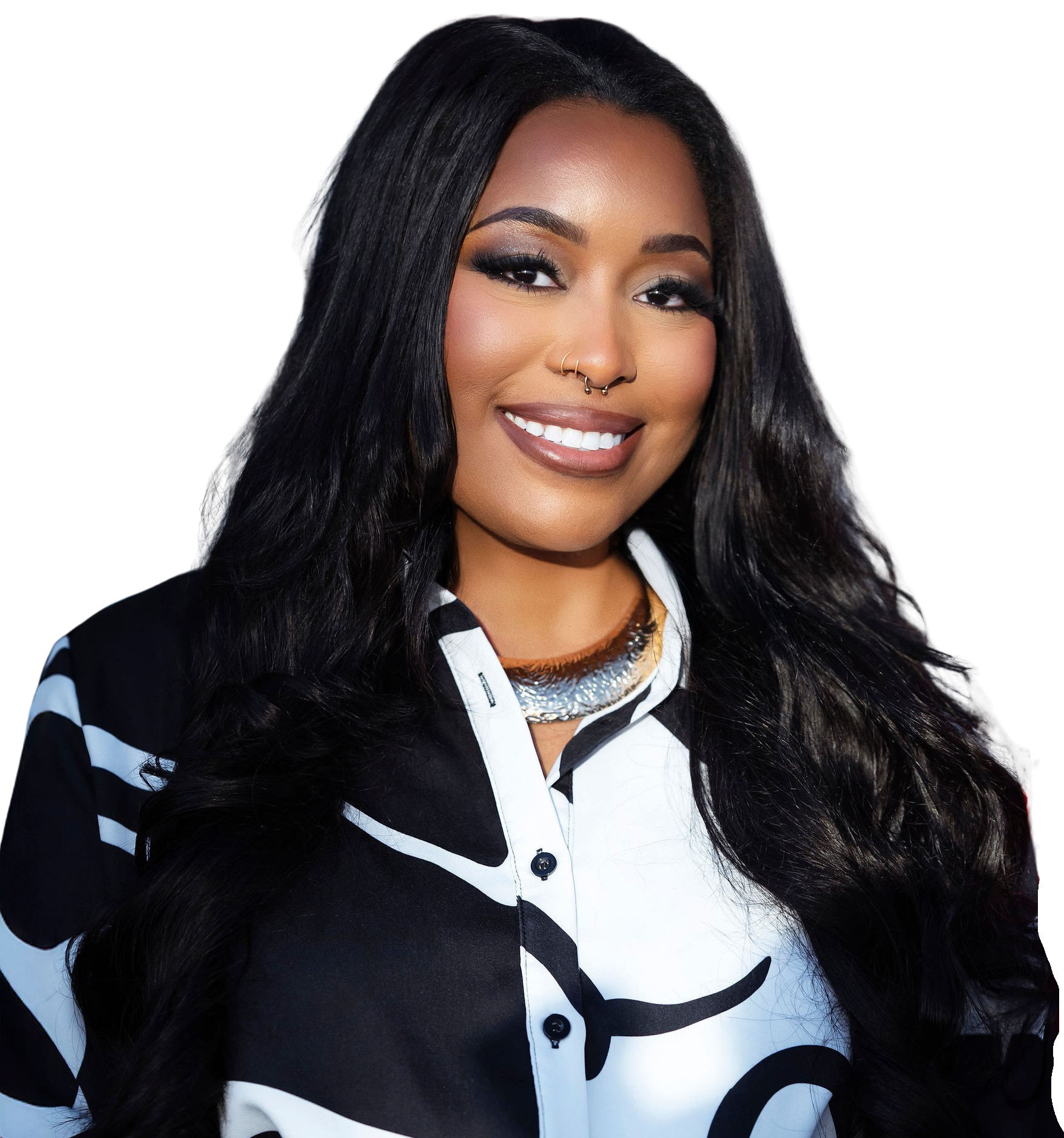 A woman with long black hair, wearing makeup, a septum, and lip piercing, smiling while dressed in a black and white patterned shirt.