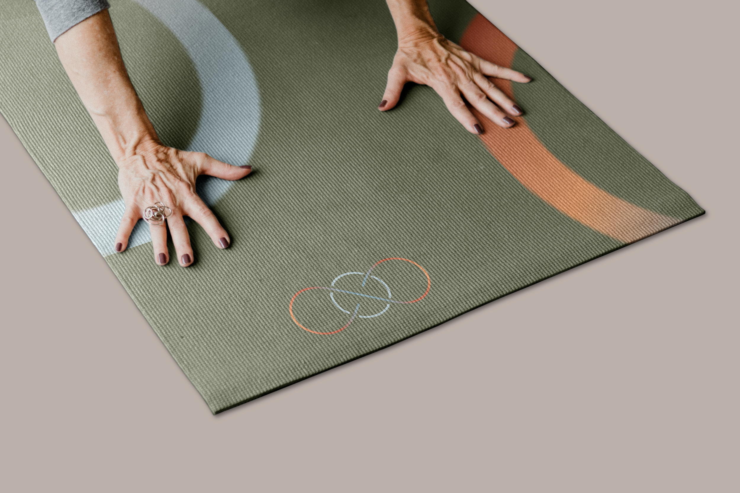 Hands in yoga pose on a green and orange yoga mat with colorful circle designs for 105F hot yoga and pilates.
