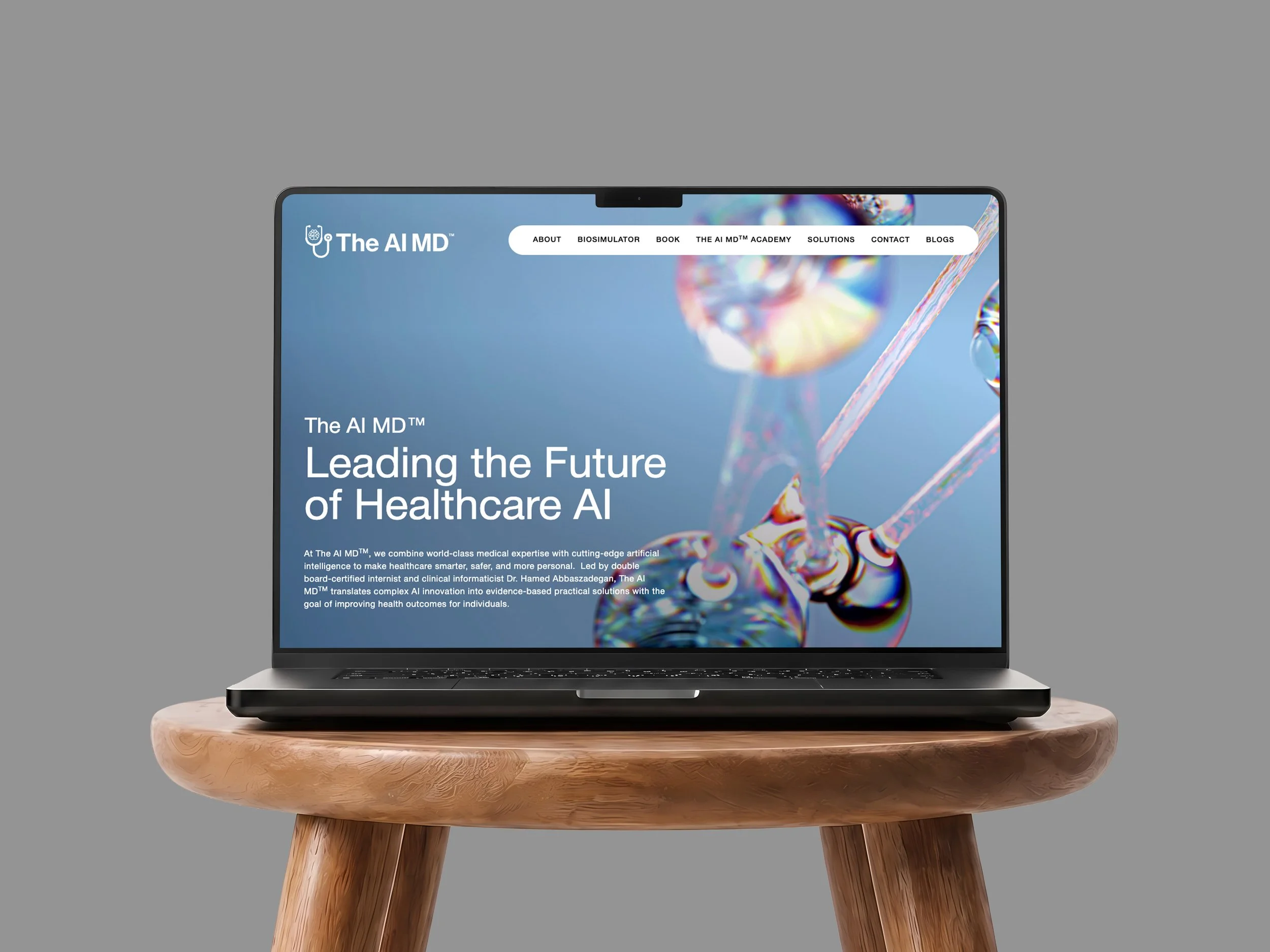 A laptop displaying a website titled The AI MD, with a science-themed background image, sitting on a wooden table against a gray background.