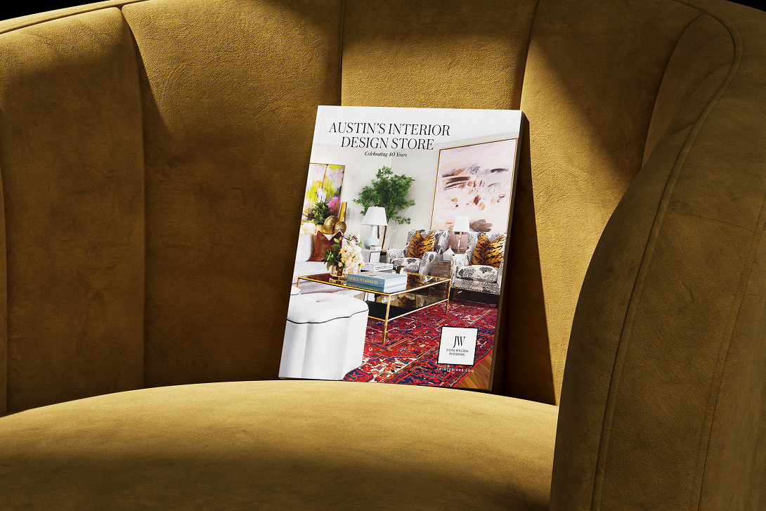 A book or magazine titled 'Austin's Interior Design Store' displaying a living room with sofas, armchairs, paintings, lamps, and a red rug