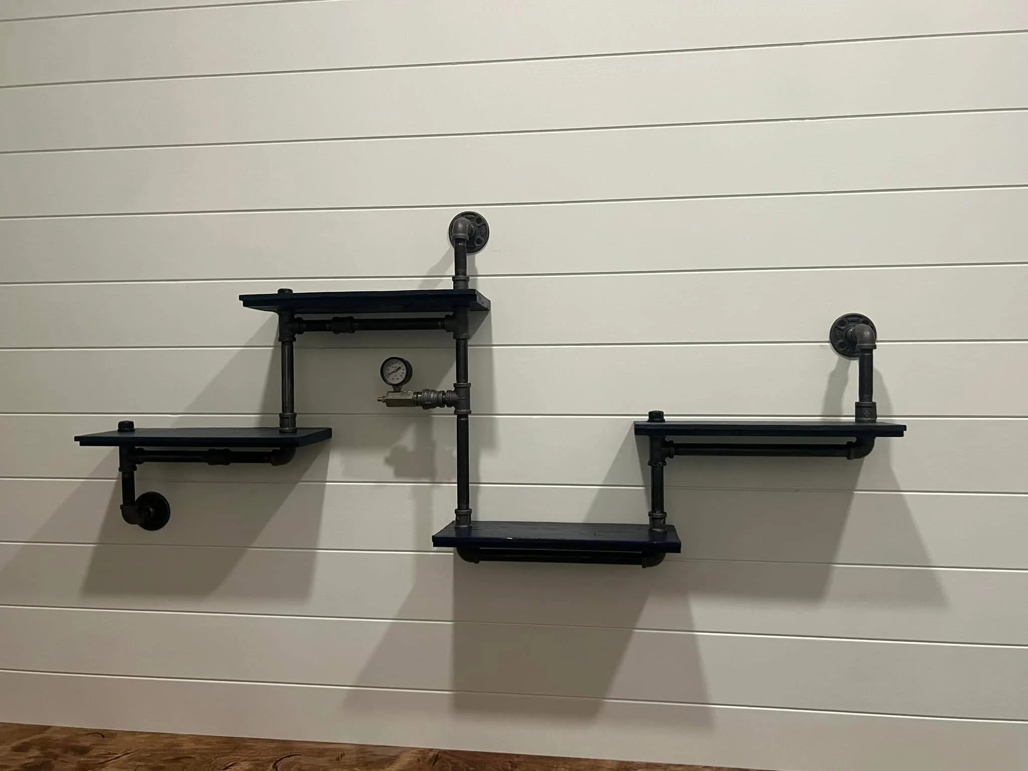 A wall with horizontal white paneling and black metal pipes arranged in a decorative pattern.