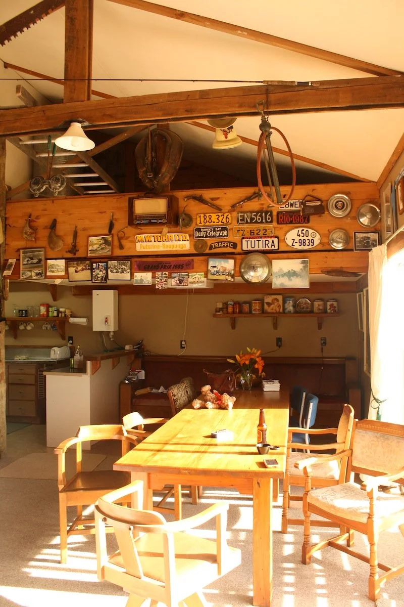 Coffee table and chairs in a sunlit room decorated with vintage signs, license plates, and framed photos on the wall.