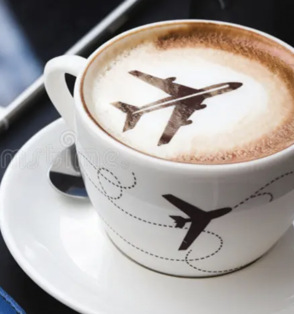 Coffee cup with airplane design in frothy milk, on a white saucer.