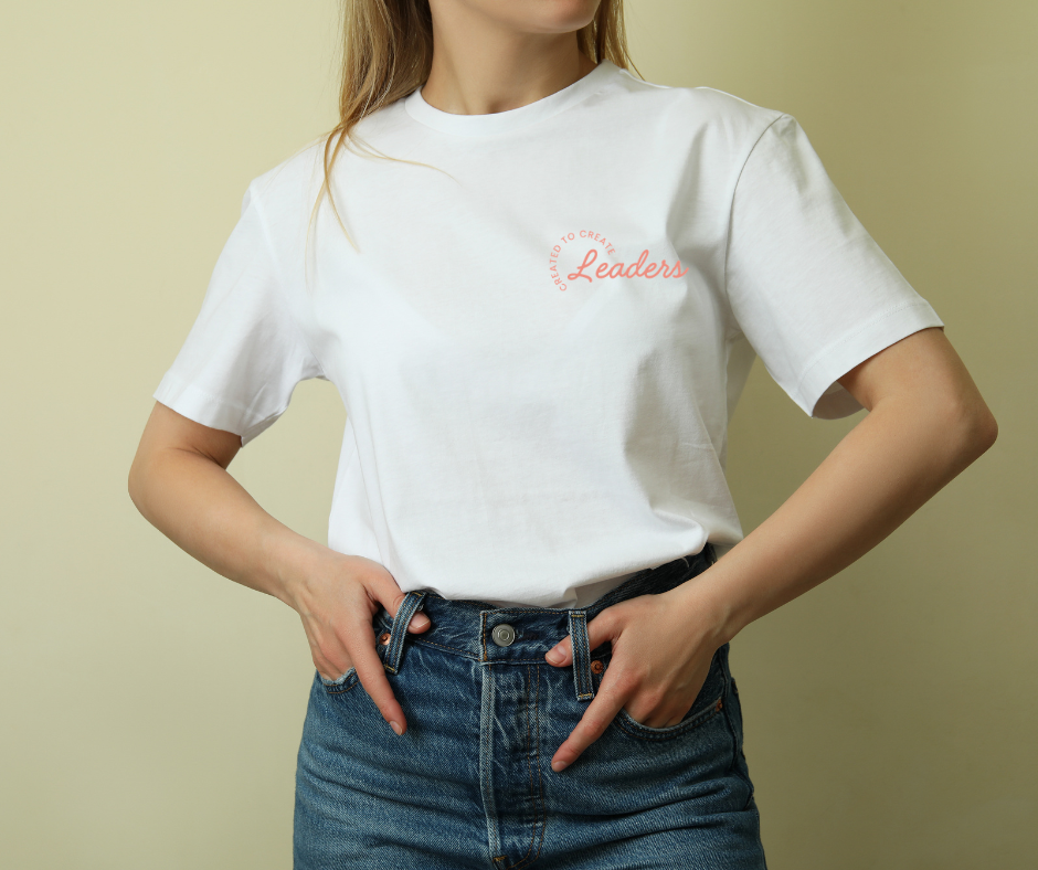 Woman wearing a white t-shirt with red text and dark blue jeans, standing against a plain background.