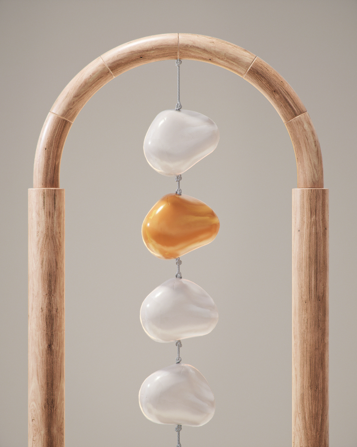 A decorative mobile with smooth, oval-shaped stones in white and brown, hanging from a wooden arch structure.