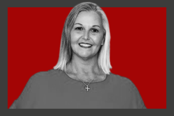Andrea Caulfield-Smith: Black-and-white portrait of a woman with shoulder-length hair, wearing a top and a cross necklace, against a red background.