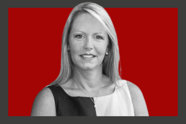 Kathryn Wallington: Black and white portrait of a woman with shoulder-length hair, wearing a sleeveless blouse, smiling, with a red background.