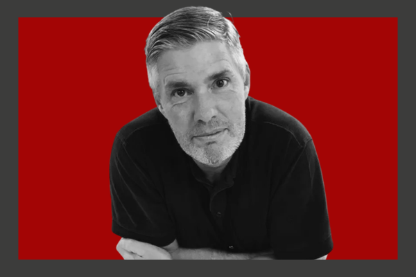 Neil Mason: A black and white photo of a middle-aged man with short hair, wearing a dark polo shirt, posing with a red background.