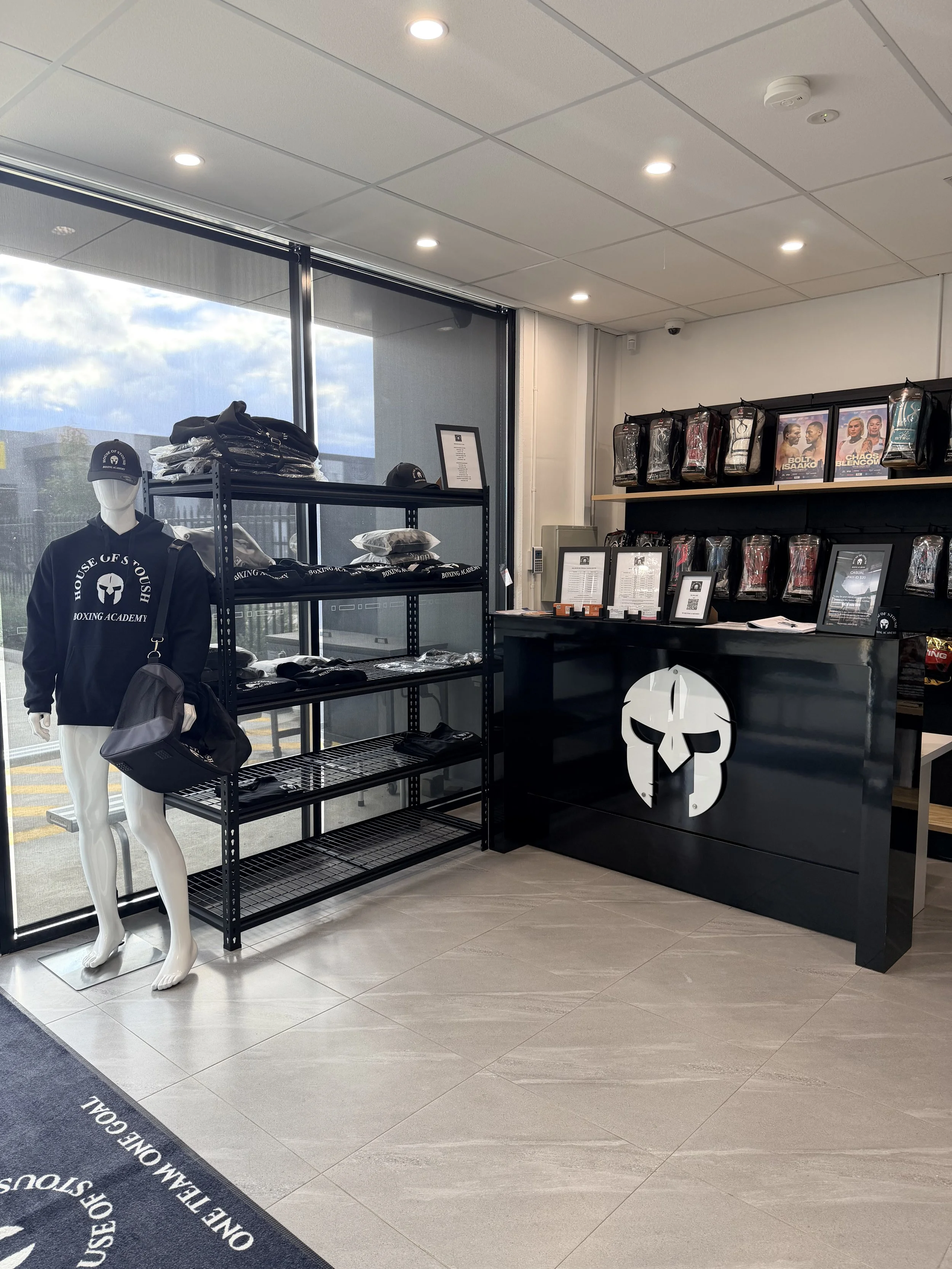 House of Stoush indoor retail reception with a mannequin wearing House of Stoush merchandise and STING products, counter with gladiator helmet from logo and personalised mats.