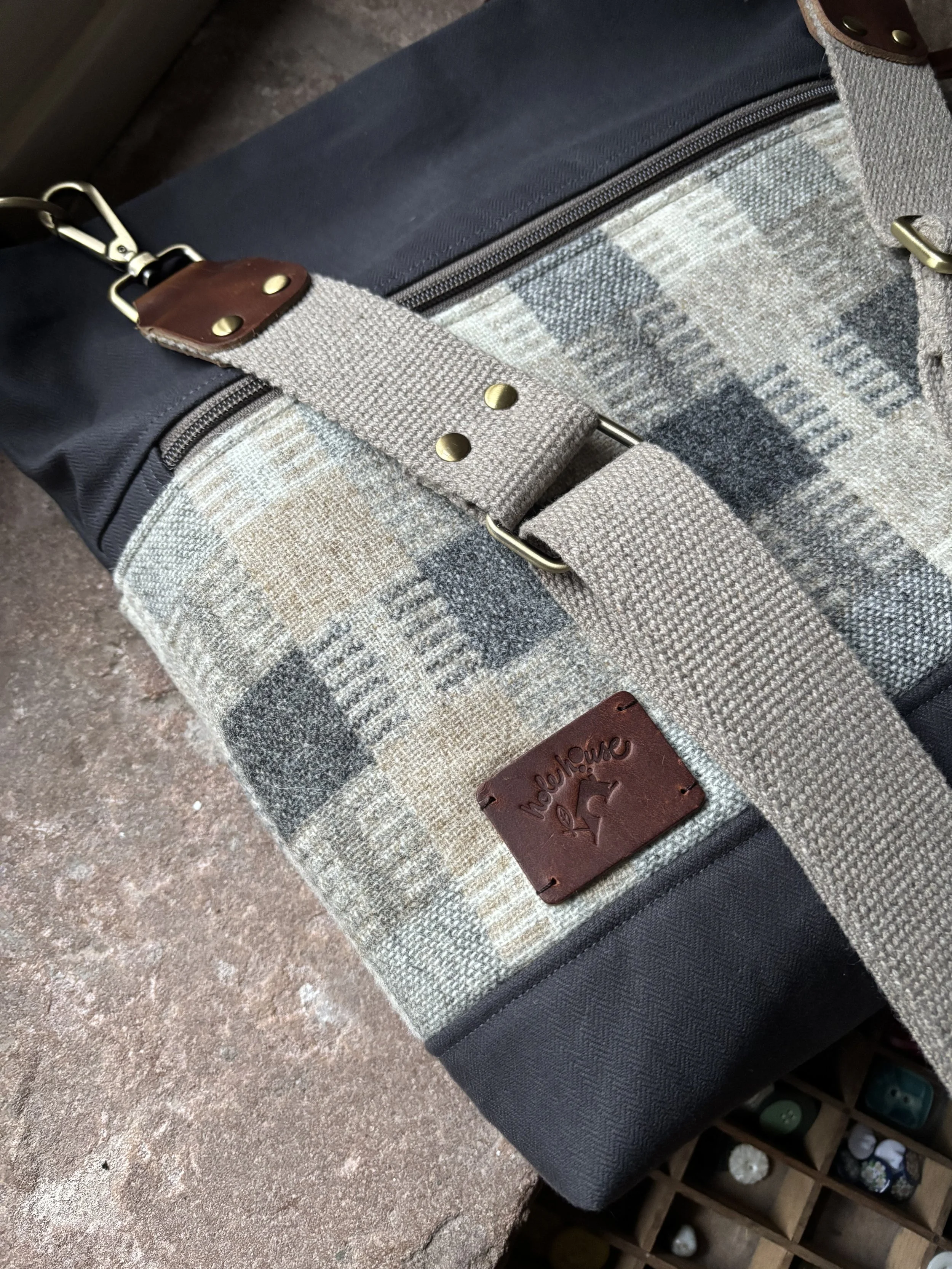A black and beige patterned bag with a leather tag that says 'Noahhouse' and a beige strap with metal hardware.