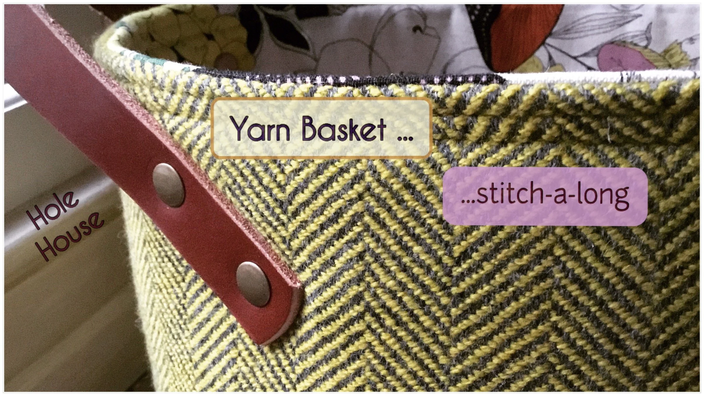 A close-up of a yarn basket with a red leather handle, decorated with yellow and black herringbone fabric. The basket has labels indicating it contains a 'Yarn Basket...' with 'stitch-a-long' instructions, and a partially visible label on the side reads 'Hole House.'