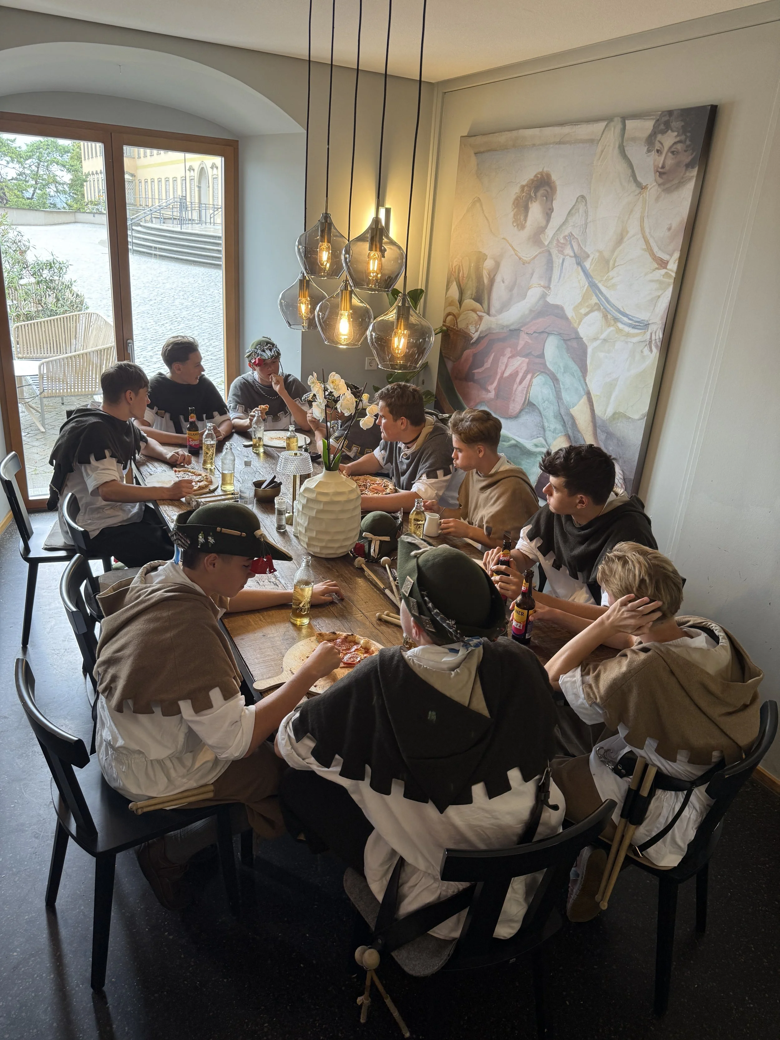 Junge Menschen, die an einem langen Esstisch im Martinus, beim Essen und Trinken.