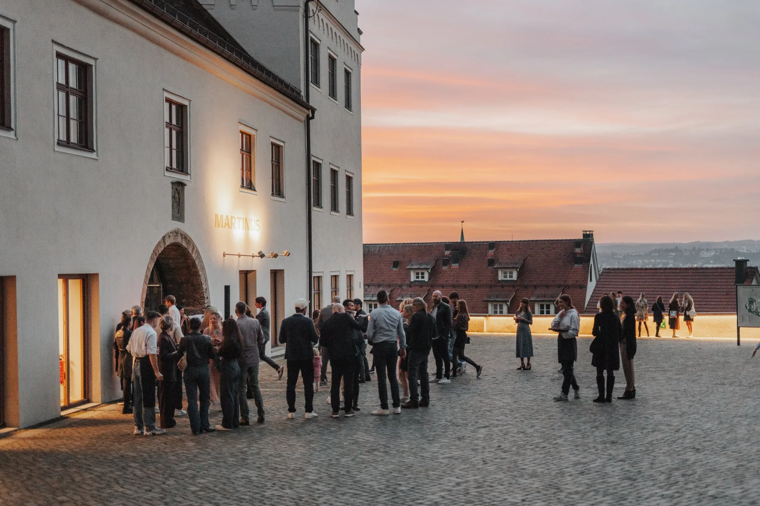 Menschen beim Empfang vor dem Martinus in Weingarten bei Sonnenuntergang.