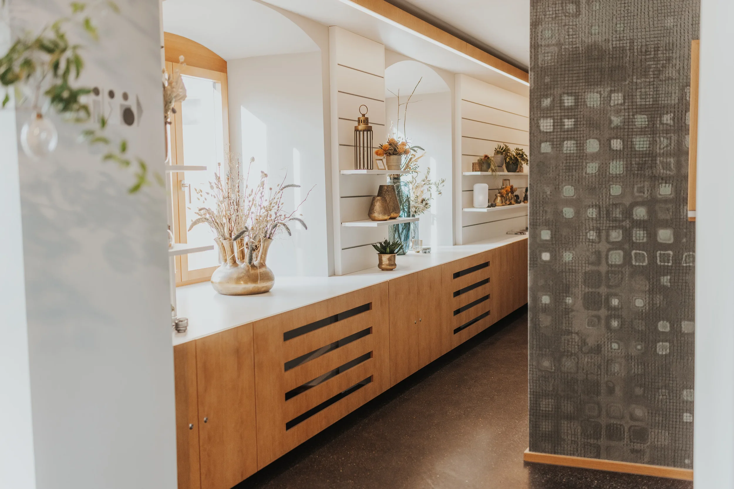 Innenansicht der modernen Veranstaltungslocation, dem Martinus, mit weißen Wänden, Holzelementen und dekorativen Vasen mit Trockenblumen.