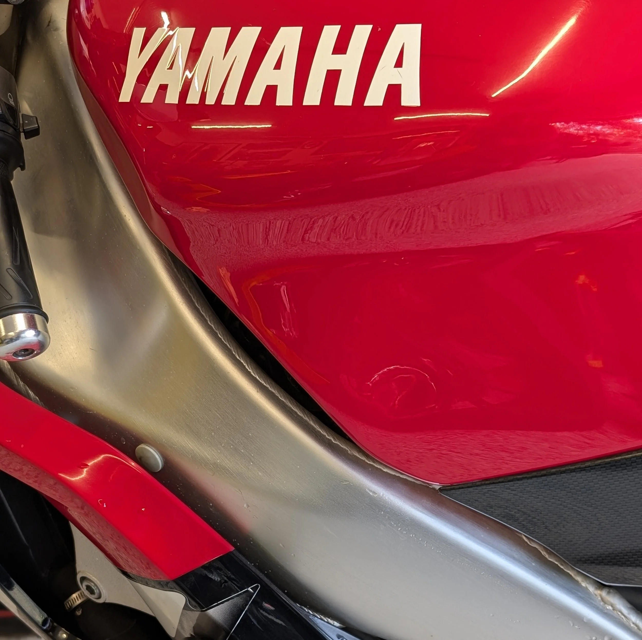 Close-up of a red Yamaha motorcycle fuel tank with the Yamaha logo on it.