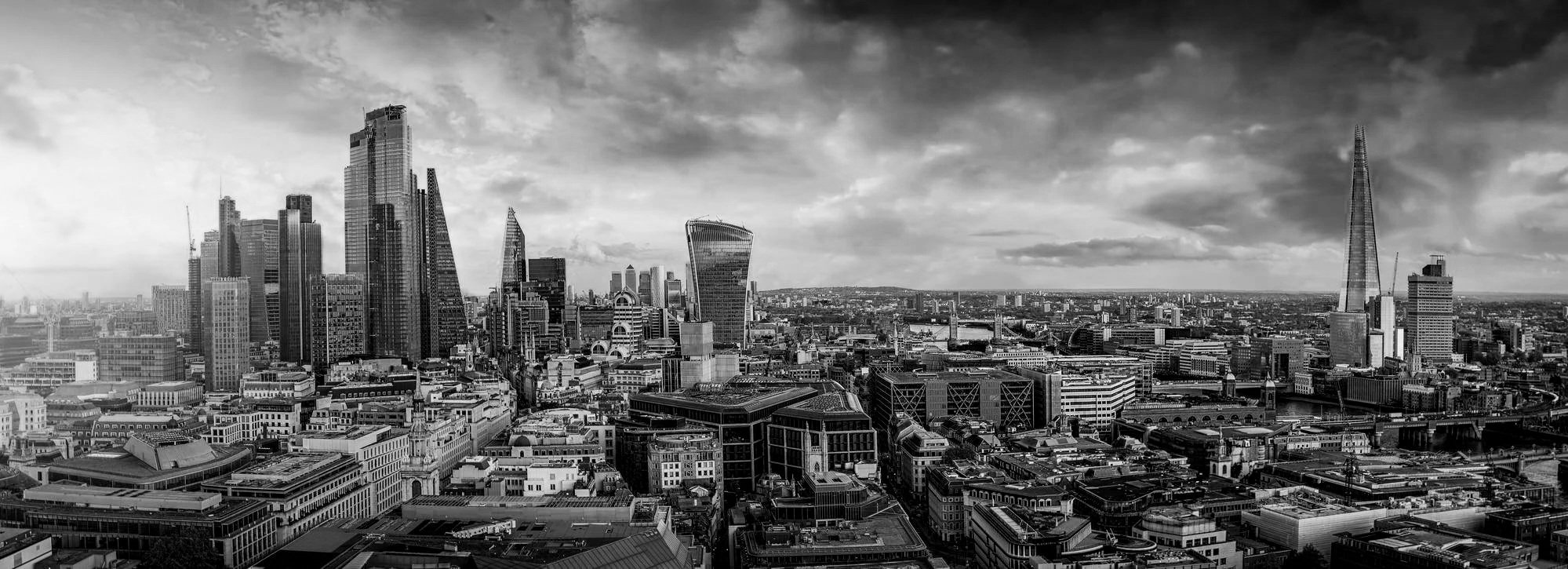 Black and white aerial view of London's skyline with various skyscrapers, including The Shard, City Hall, and the Walkie Talkie building.