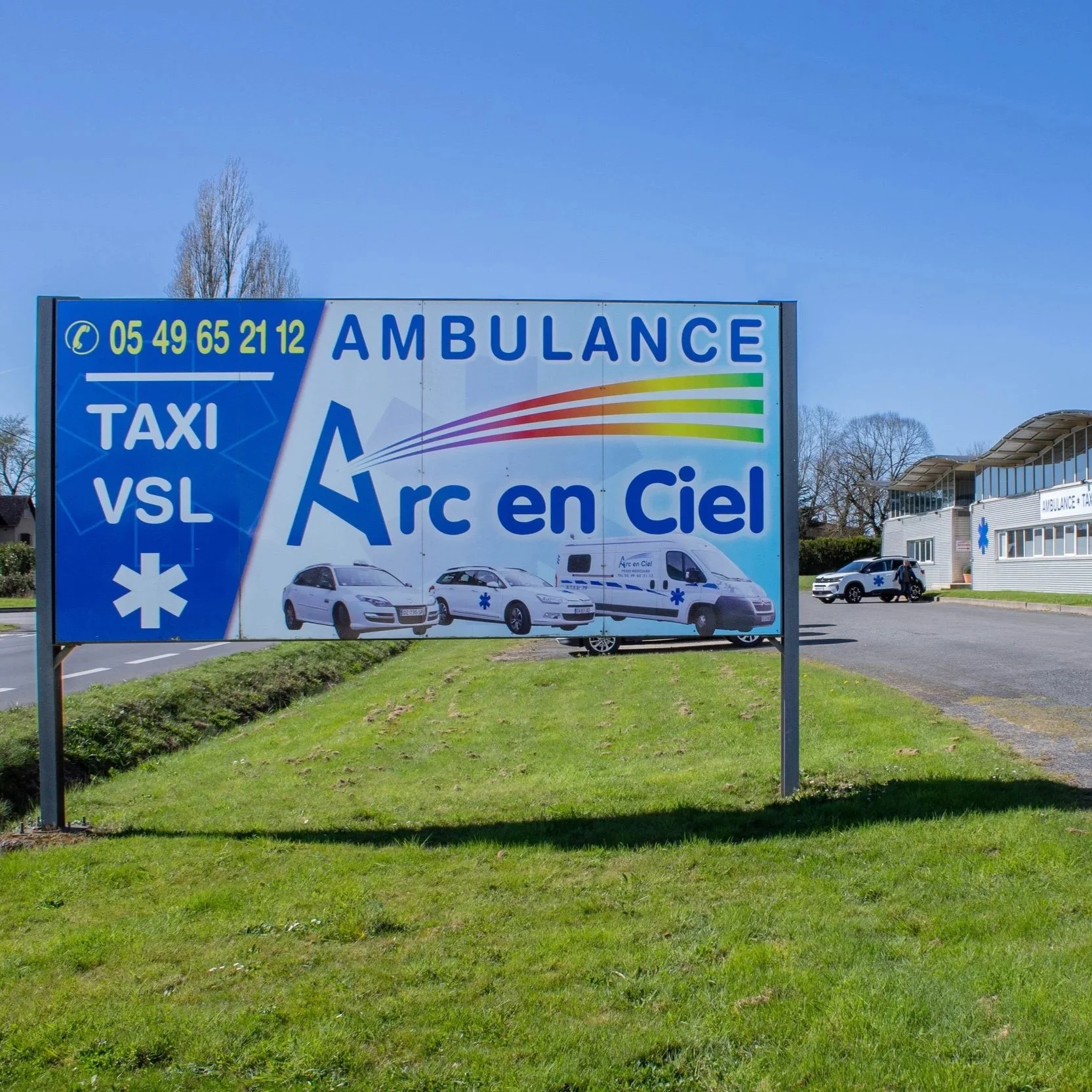 Panneau publicitaire indiquant une clinique ambulatoire, avec un numéro de téléphone et des véhicules d'urgence stationnés devant le centre médical.