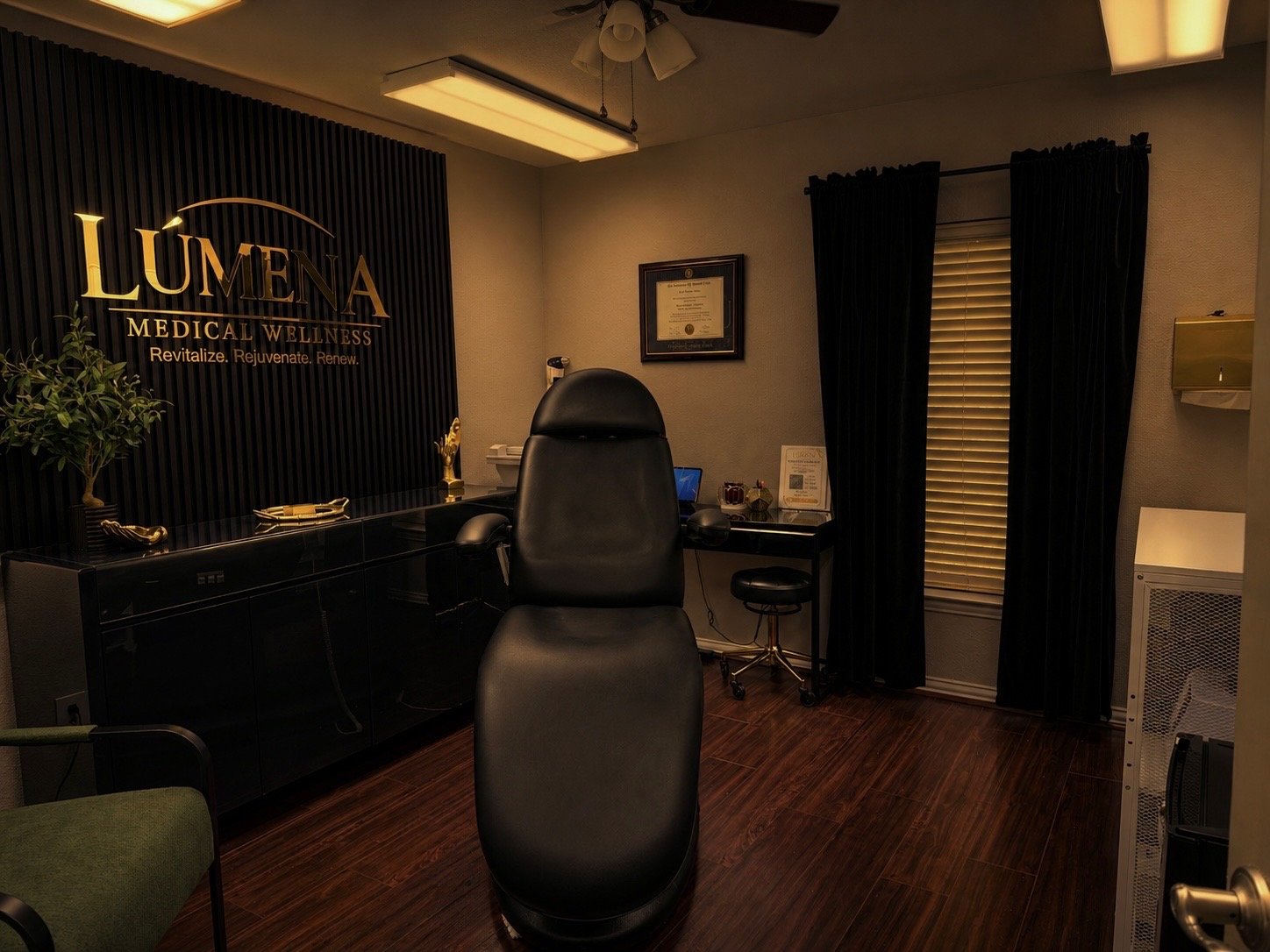Private treatment room at LÚMENA Medical Wellness in Arlington, Texas, featuring a comfortable medical chair and gold LÚMENA wall logo.