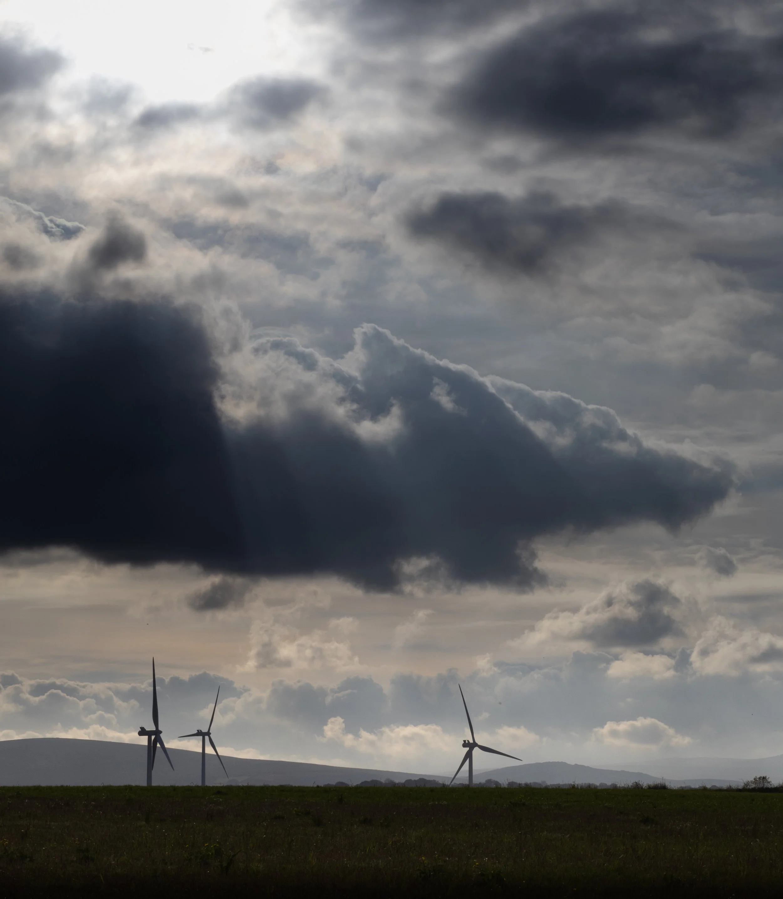 Landscape with wind turbines on a grassy field under a cloudy sky.