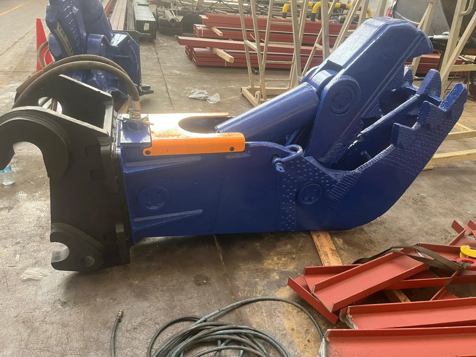 Estructura metálica grande, pintada de azul, en un taller o fábrica, con varias herramientas y piezas alrededor.