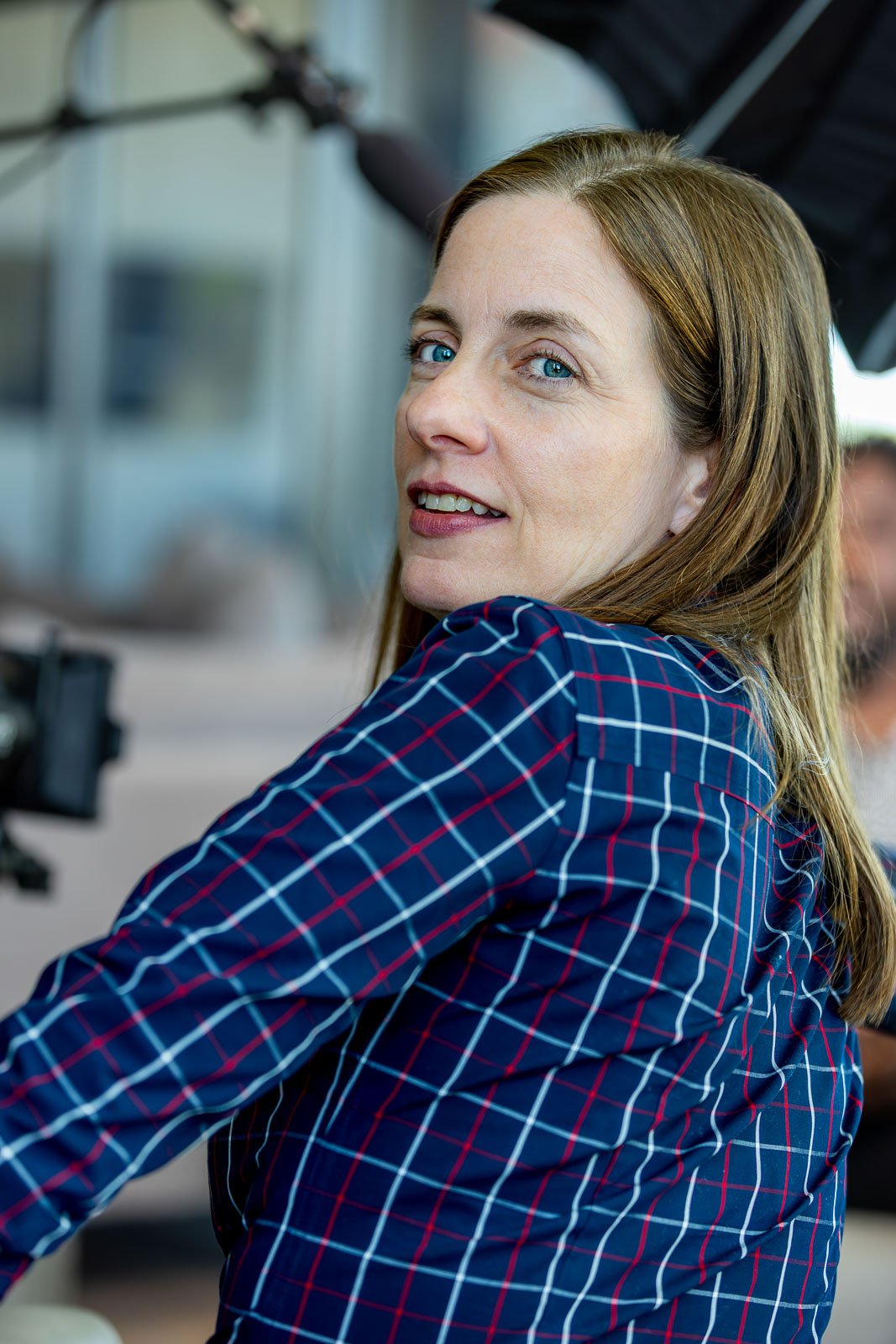 Cynthia Head, producer, wearing a blue plaid shirt, looking over her shoulder and smiling at the camera.