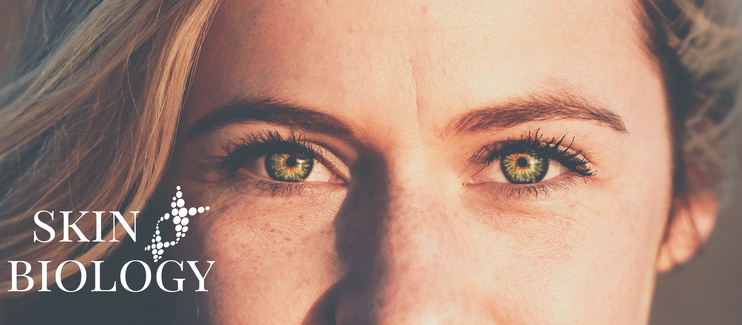 A woman with piercing green eyes and blonde hair, close-up portrait, with text overlay reading 'Skin Biology' and a DNA double helix graphic.