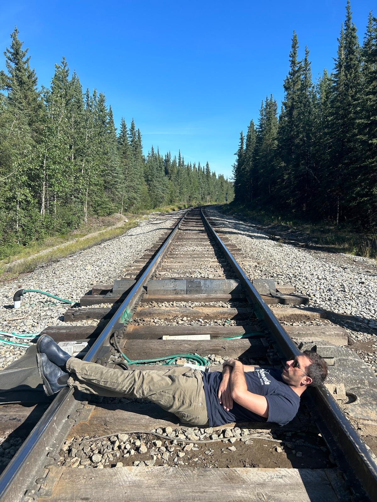 A man lies across an abandoned railway track, arms crossed
