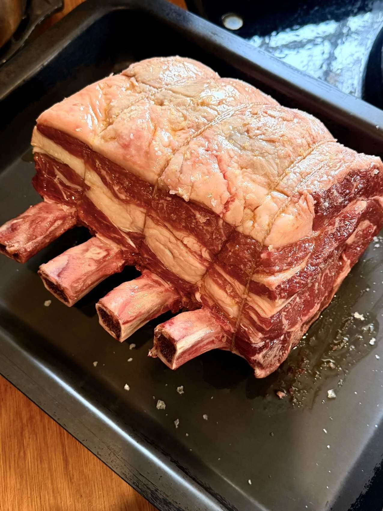 A French-trimmed rib of beef, a special-occasion cut, resting on a tray before roasting.