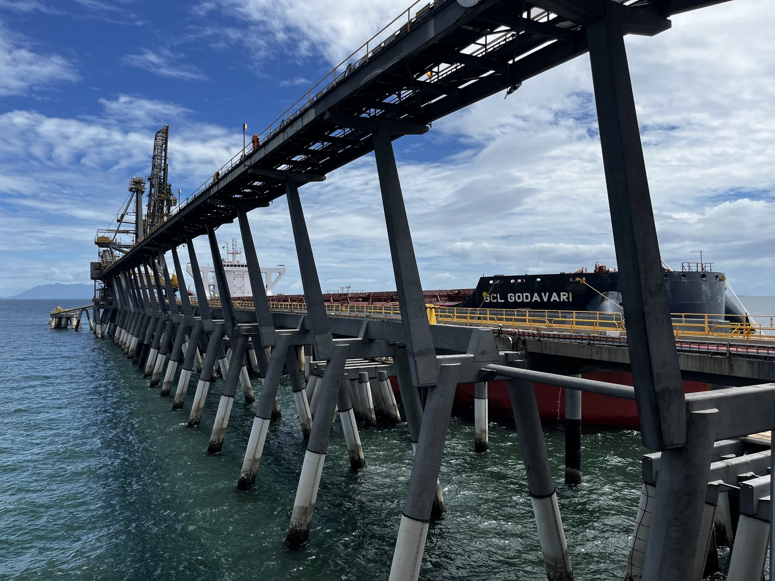 View of a large ship docked at a pier, with industrial structures, Copyright of Stephanie Munns Heilsa Consulting Pty Ltd