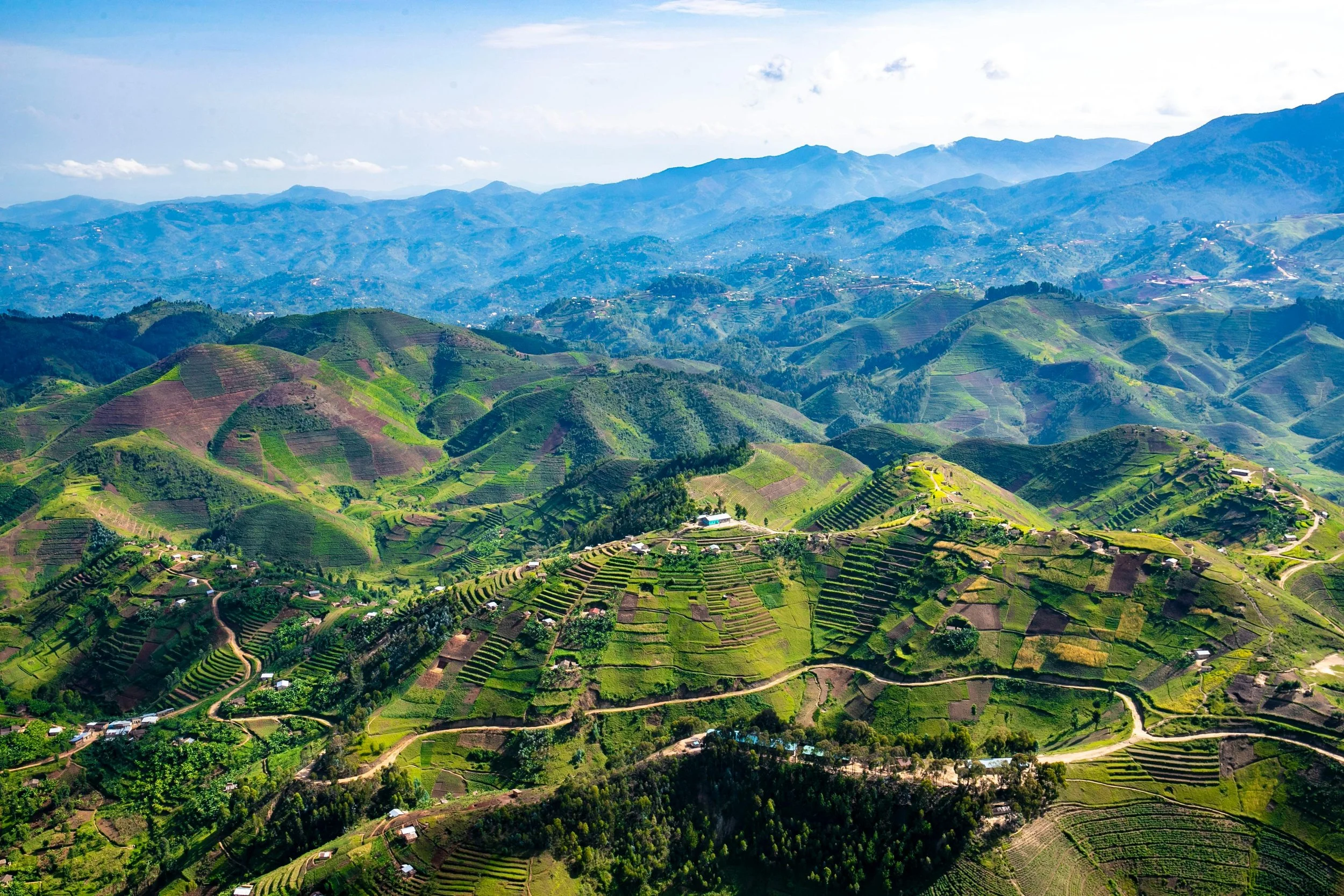Paisaje de montañas verdes con terrazas agrícolas y pequeños pueblos en un entorno rural.