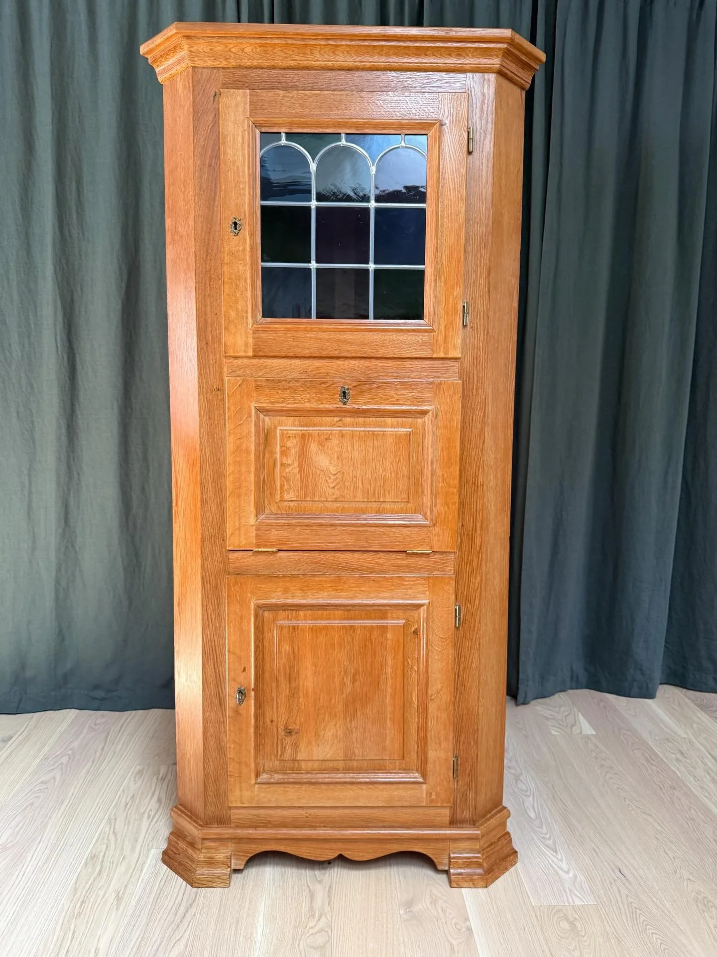 *AVAILABLE* &mdash; $600

Antique Danish Oak Corner Cabinet with Leaded Glass Door &amp; Drop Front

Solid oak corner cabinet from Denmark, in the style of Henning Kj&aelig;rnulf. Three-section construction: upper display compartment behind a leaded 