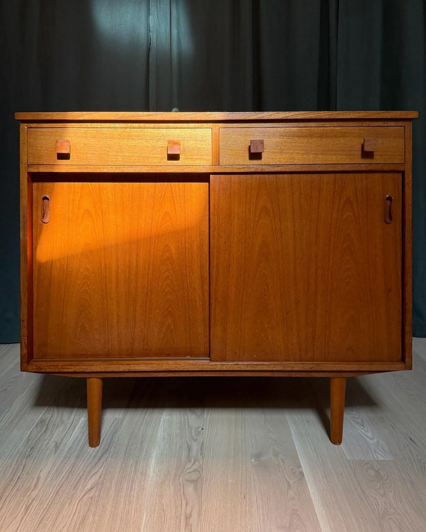 *AVAILABLE* &mdash; $975

Danish Teak Compact Sideboard Record Cabinet, Scandinavian, circa 1960s.

Two full-width drawers over two sliding doors, fitted with square block pulls in a contrasting darker teak. Sliding doors have carved oval recessed pu