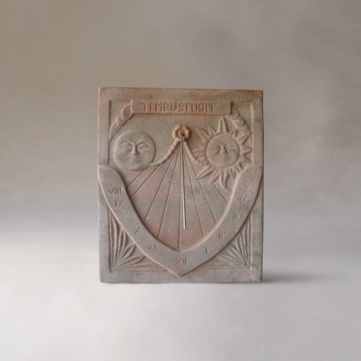 A decorative sundial with a carved sun and moon faces, Roman numerals, and the Latin phrase 'Tempus Fugit' at the top, showing a shadow indicating the time.