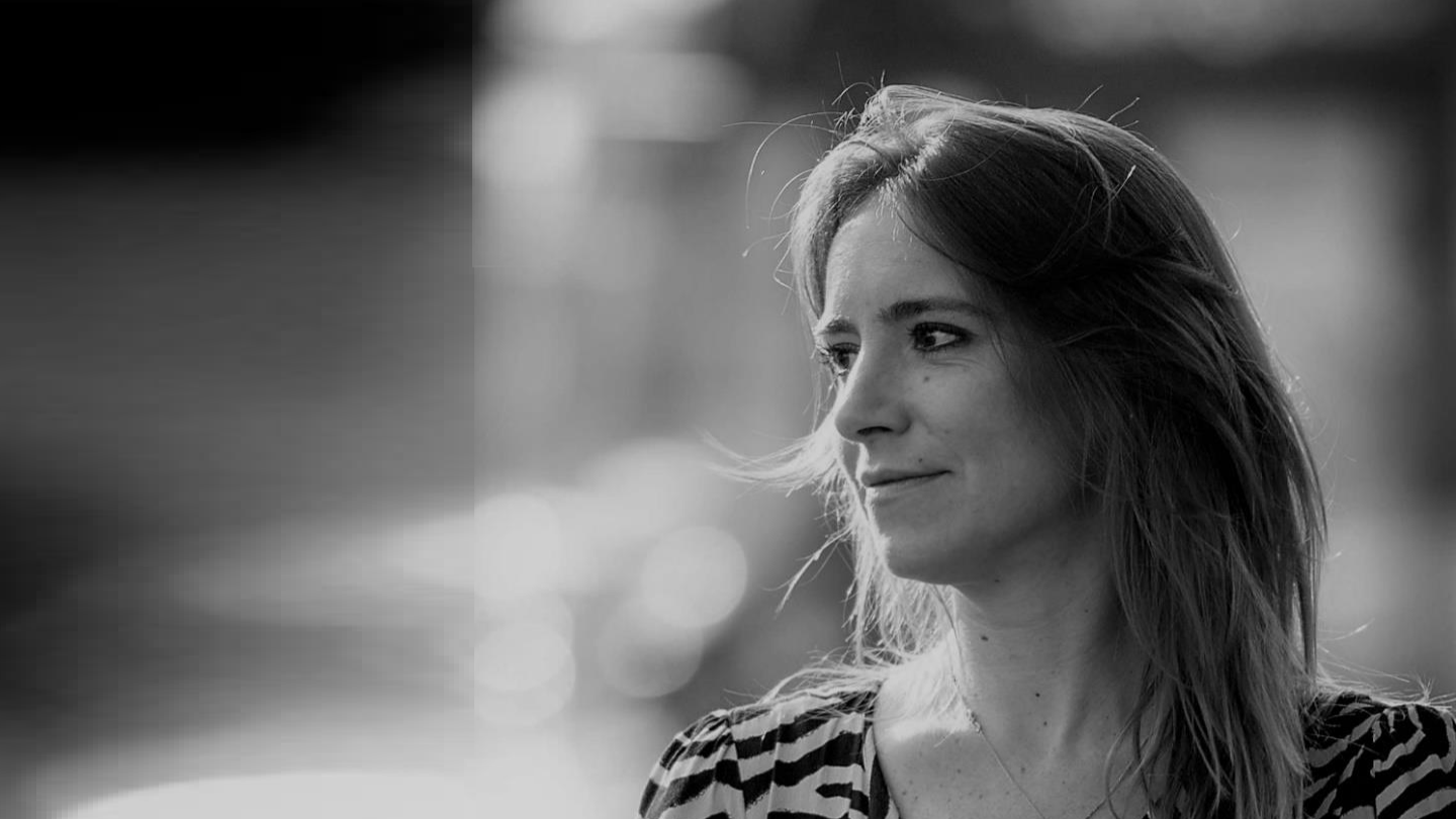 Black and white portrait of a woman with long hair, looking to the right, outdoors.