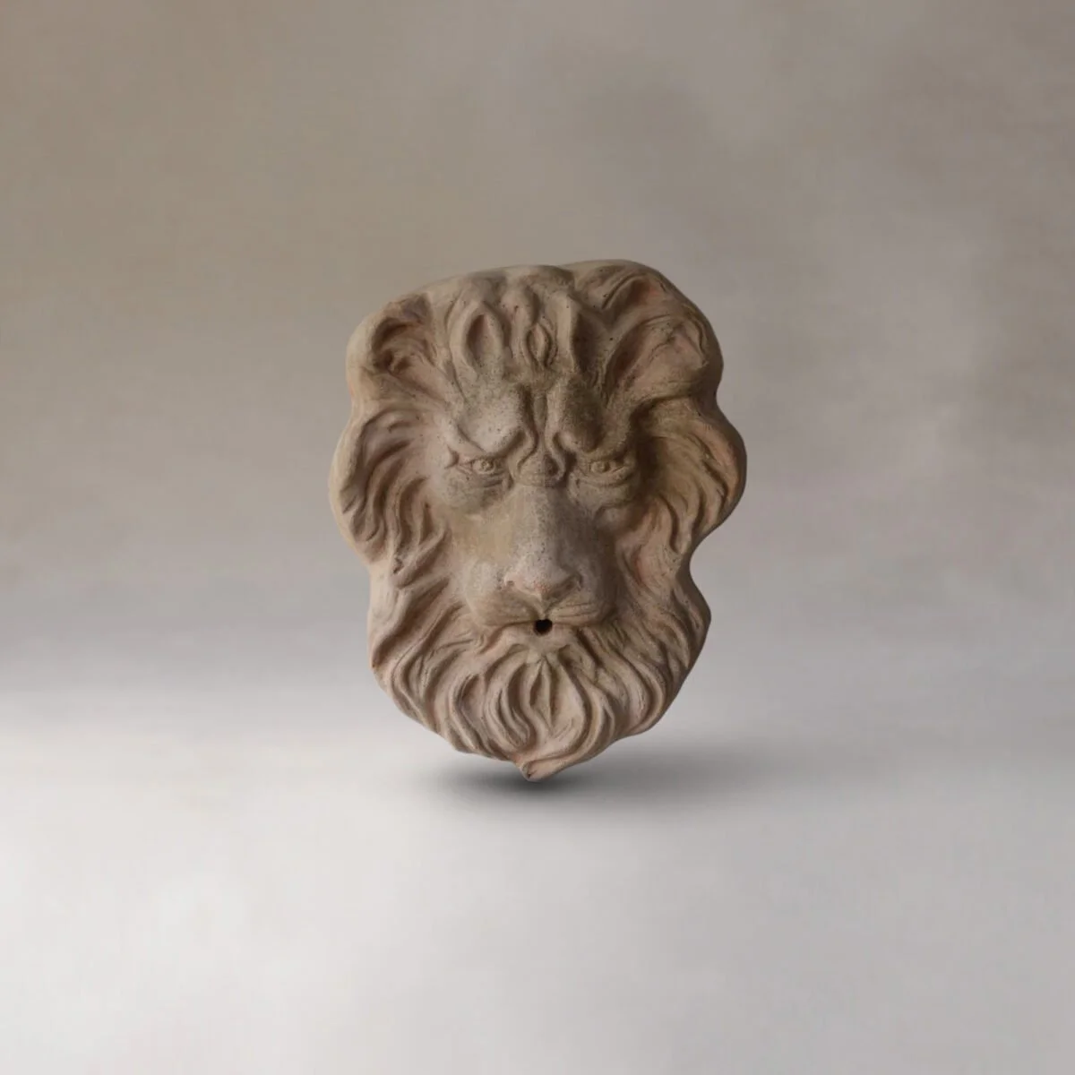 A sculpture of a lion's head, carved from a light-colored material, displayed against a plain background.