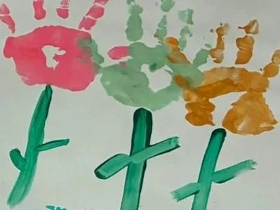 Child's watercolor painting of colorful flowers with green stems, red, orange, and yellow petals, on white paper.