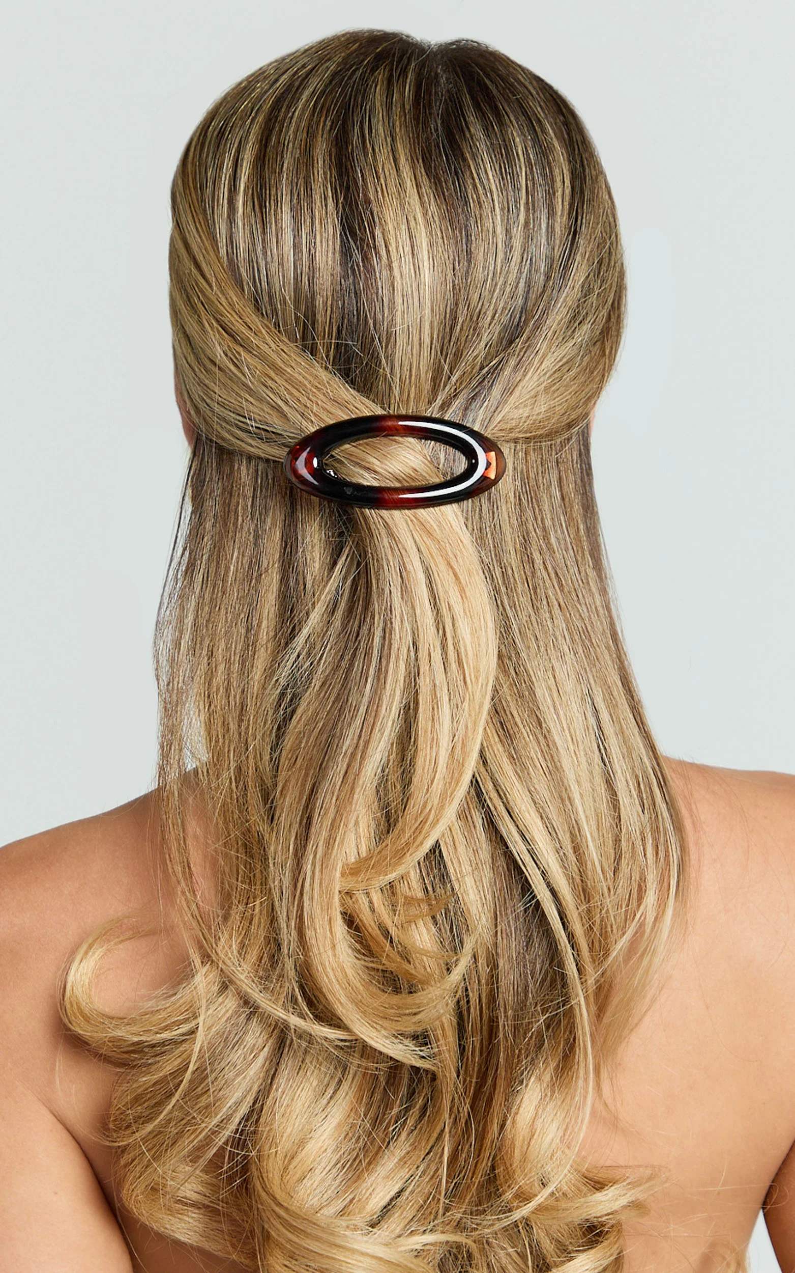 Back of a woman with long, wavy blonde hair secured with a tortoise shell hair clip.