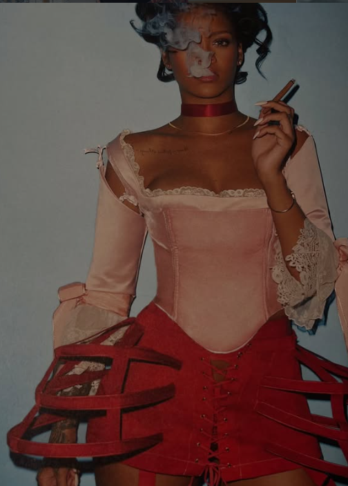 A woman with dark curly hair smoking a cigarette, wearing a pink corset top with lace details, a red choker, and a red skirt with cut-out sections, standing against a plain background.