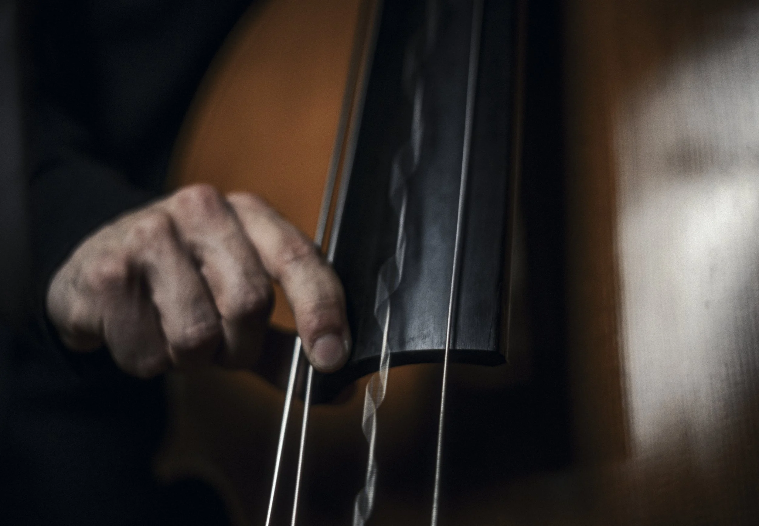 Close-up of a person's hand plucking the strings of an acoustic guitar.