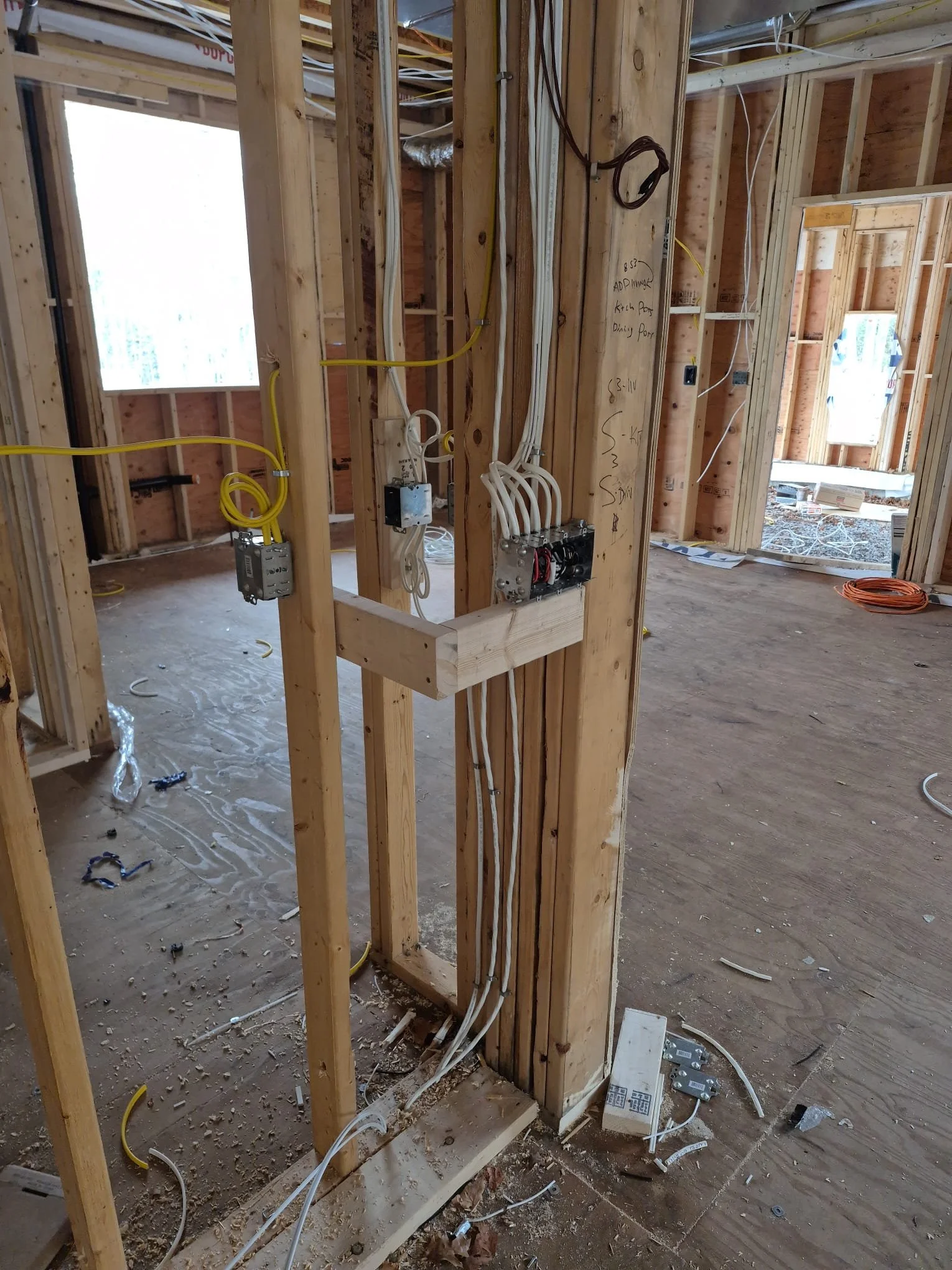 Electrical wiring and outlets installed within the wooden framing of a house under construction.