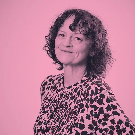 Portrait of a woman with curly hair wearing a leopard-print top against a pink background.