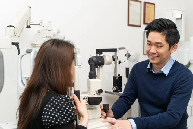 Optometrist conducting an eye exam on a patient using a slit lamp in an eye clinic.