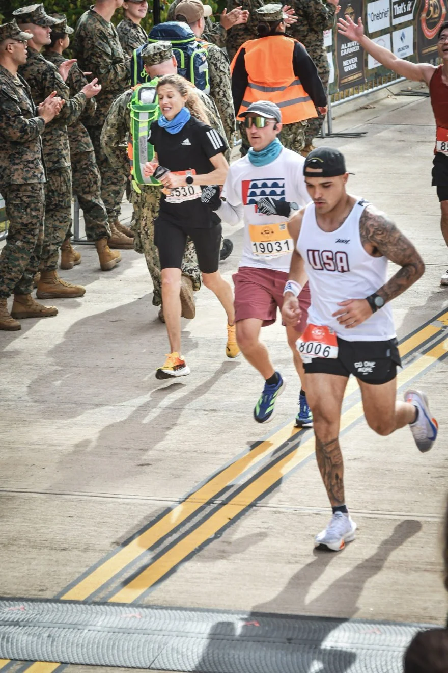 Runners participating in a marathon race, passing a group of soldiers clapping and cheering on the sidelines.