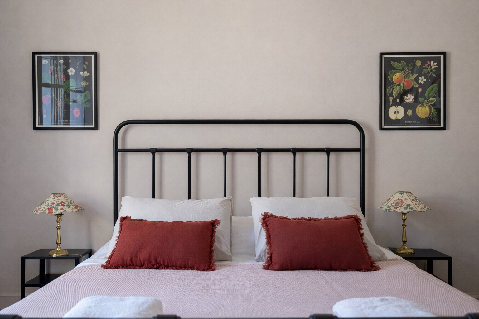 Bedroom with a double bed, nightstands, lamps, and paintings of fruit on the wall